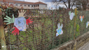 Na fotografii jsou obrázky Země + ručiček dětí, výzdoba plotu školy 